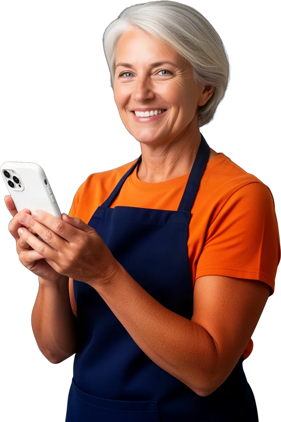 Smiling woman with silver hair in an orange t-shirt and navy apron holding a smartphone in a white case